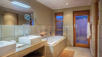 Un baño moderno con dos lavamanos, una bañera amplia y una zona de ducha con mampara de vidrio.