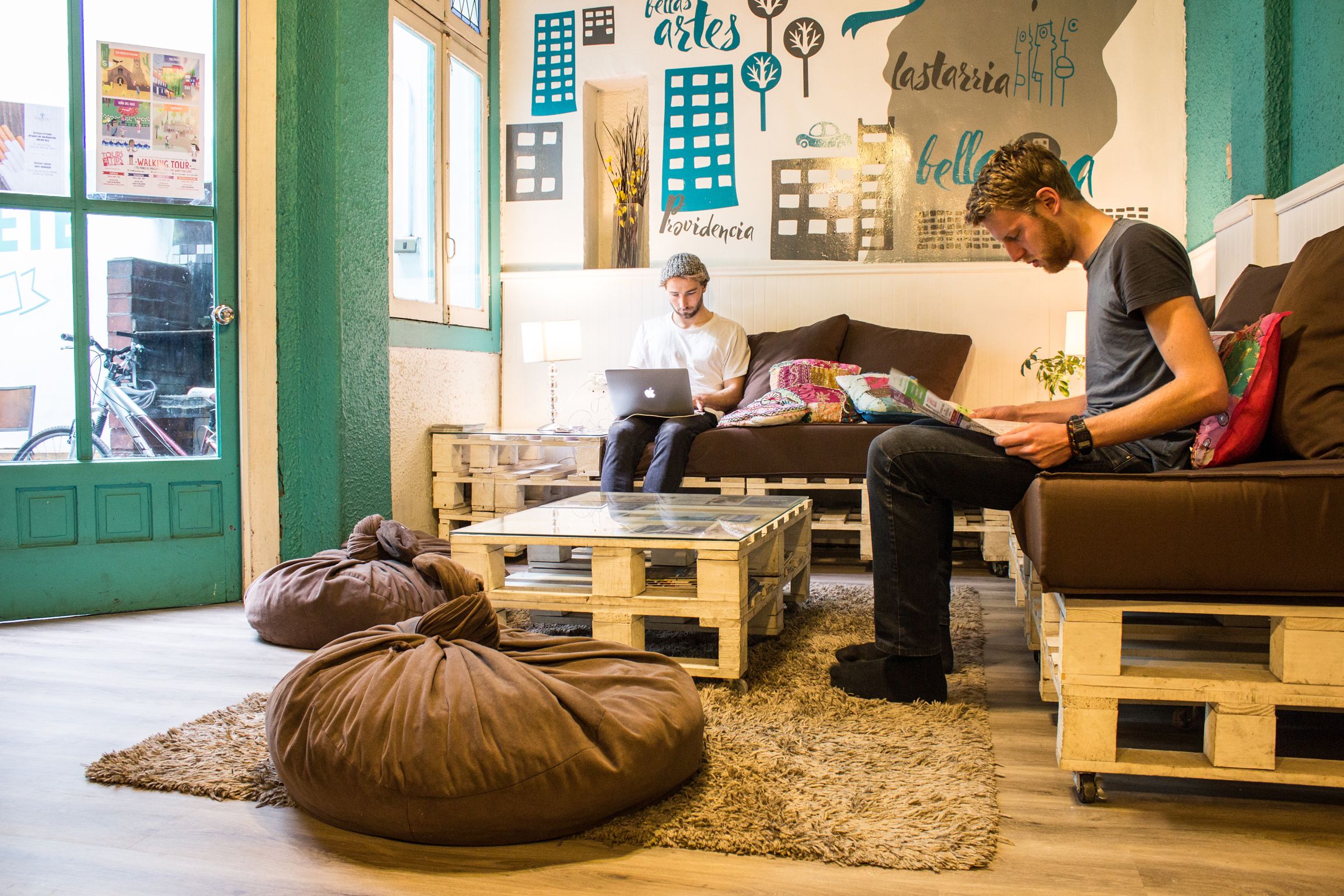 Una habitación acogedora con una puerta verde, muebles de madera y un mural en la pared.