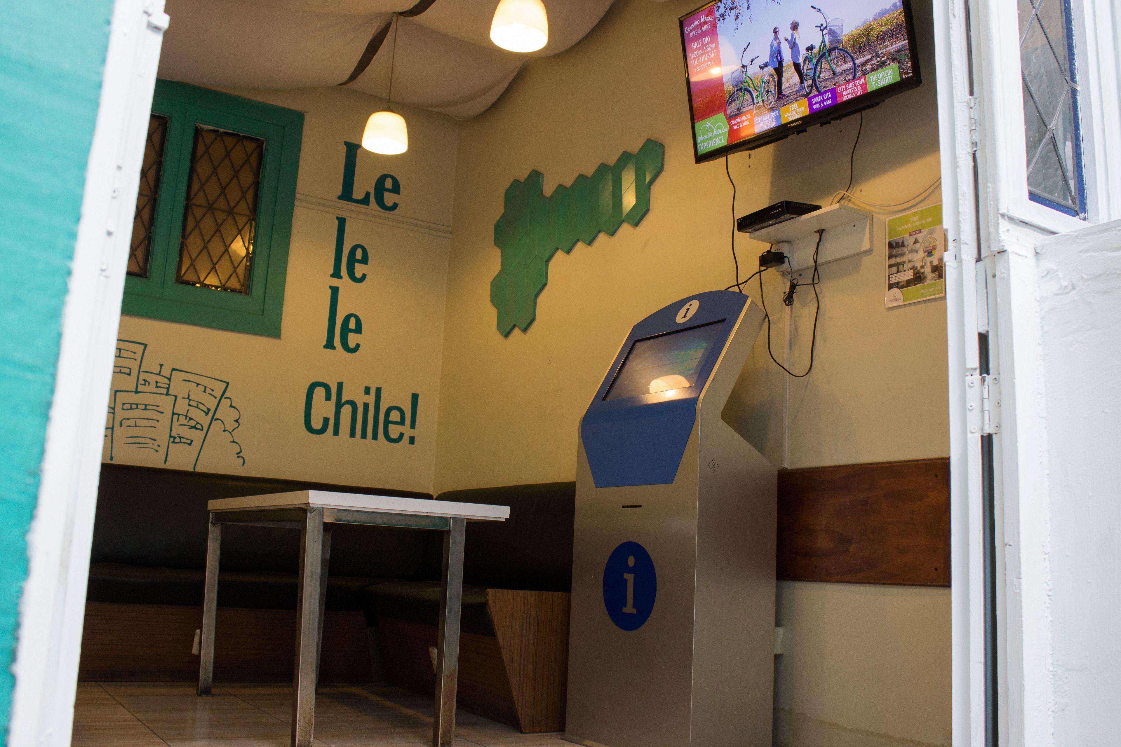 Una habitación con una mesa, un televisor montado en la pared y un mapa de Chile.