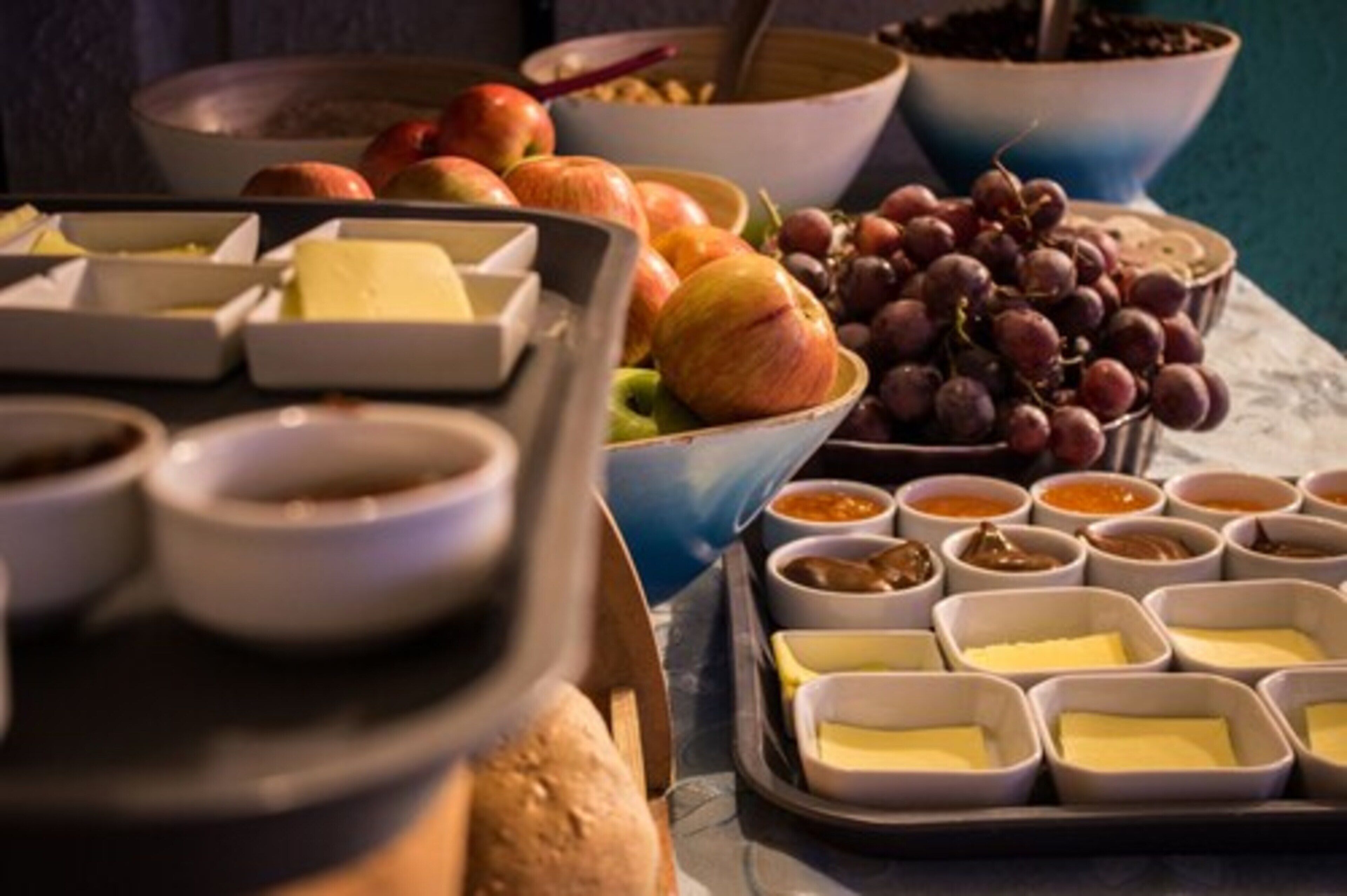 A buffet table with various food items including fruits, cheeses, and sauces.