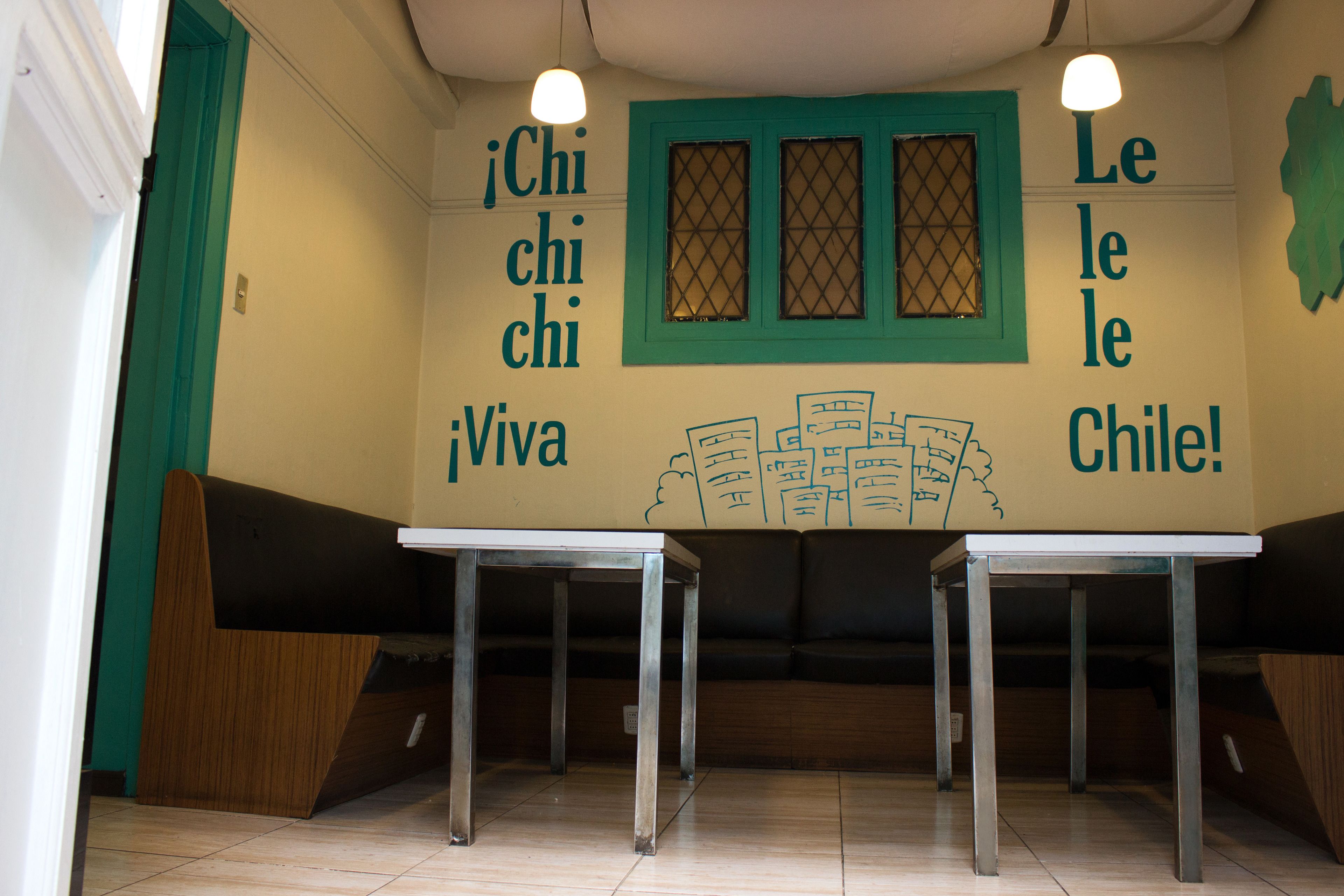 Interior de un restaurante con una zona de cabinas, una mesa y una pared decorada con textos e ilustraciones.