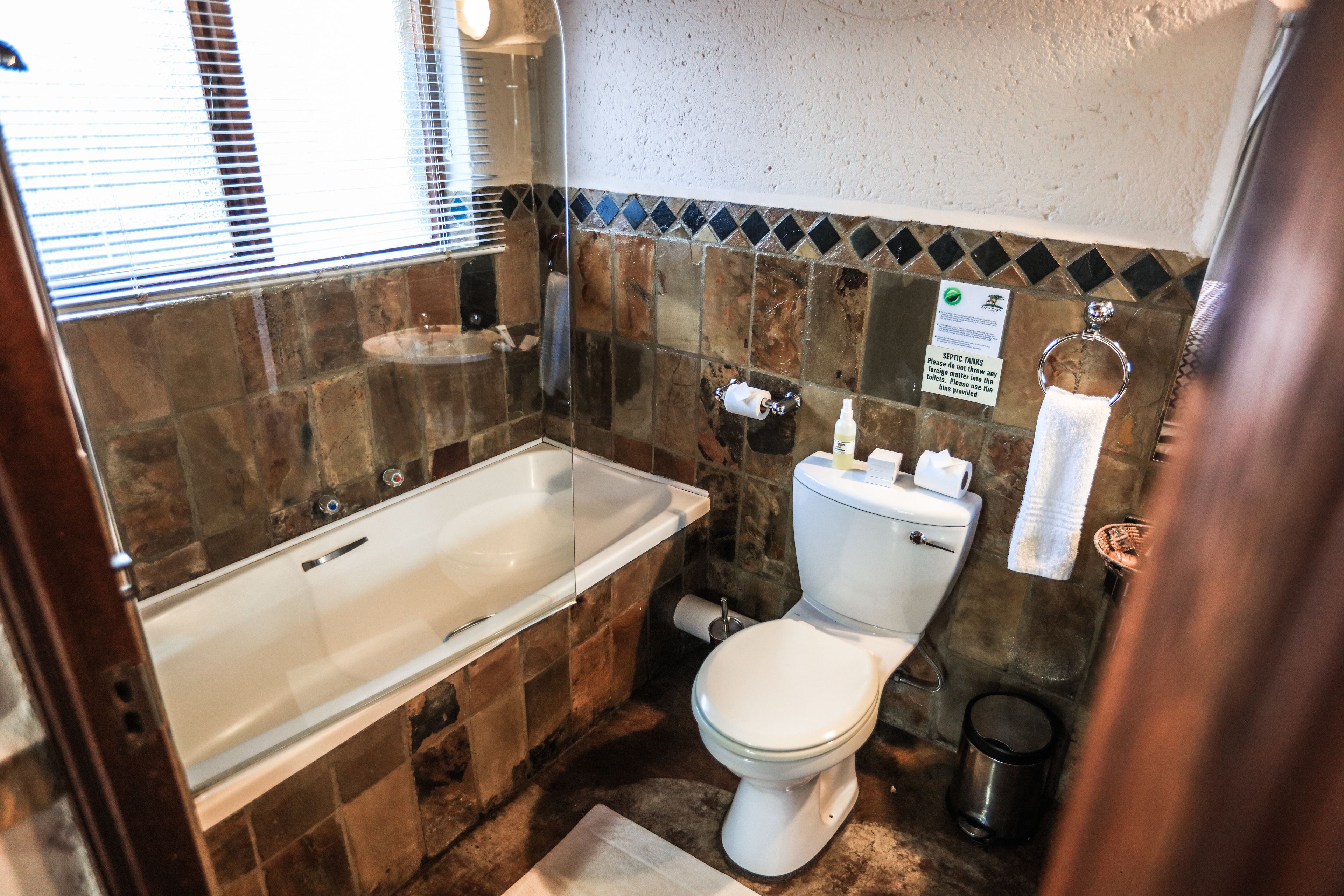 Ein Badezimmer mit Badewanne, Toilette und Wandplatten.