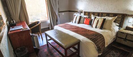 A bedroom with a large bed, a desk, and a chair.
