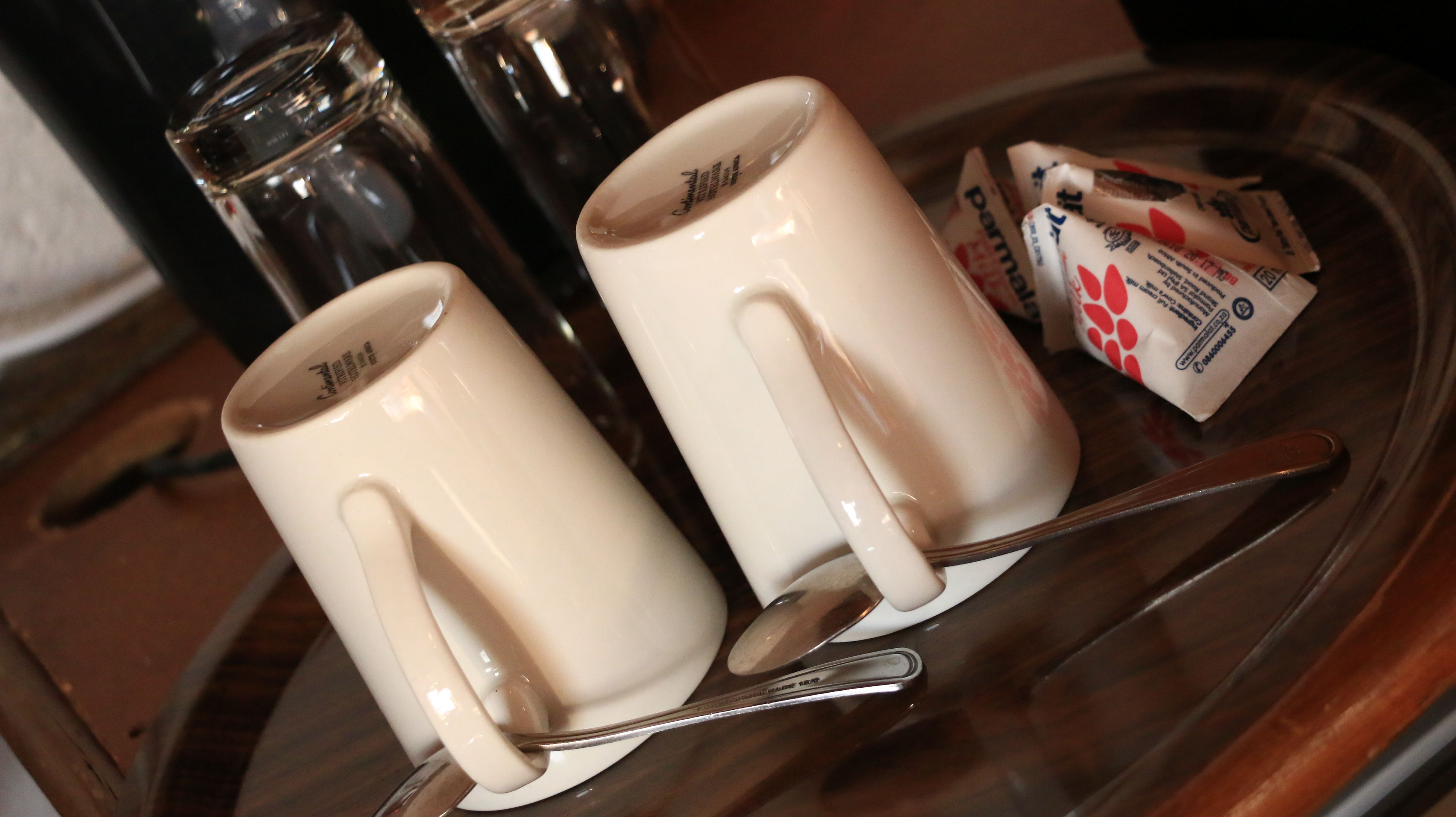 Dos tazas blancas de cerámica con asa sobre una bandeja.