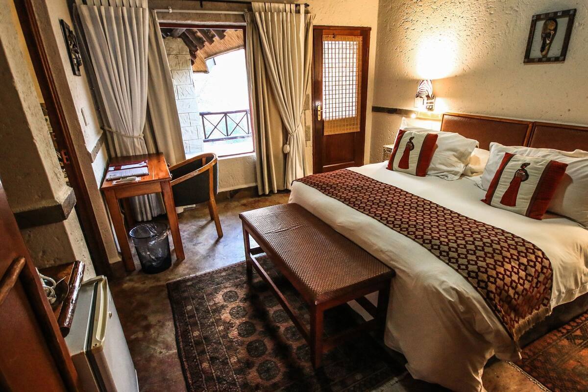 Ein Schlafzimmer mit Bett, Nachttisch, Sessel und einem kleinen Fenster.