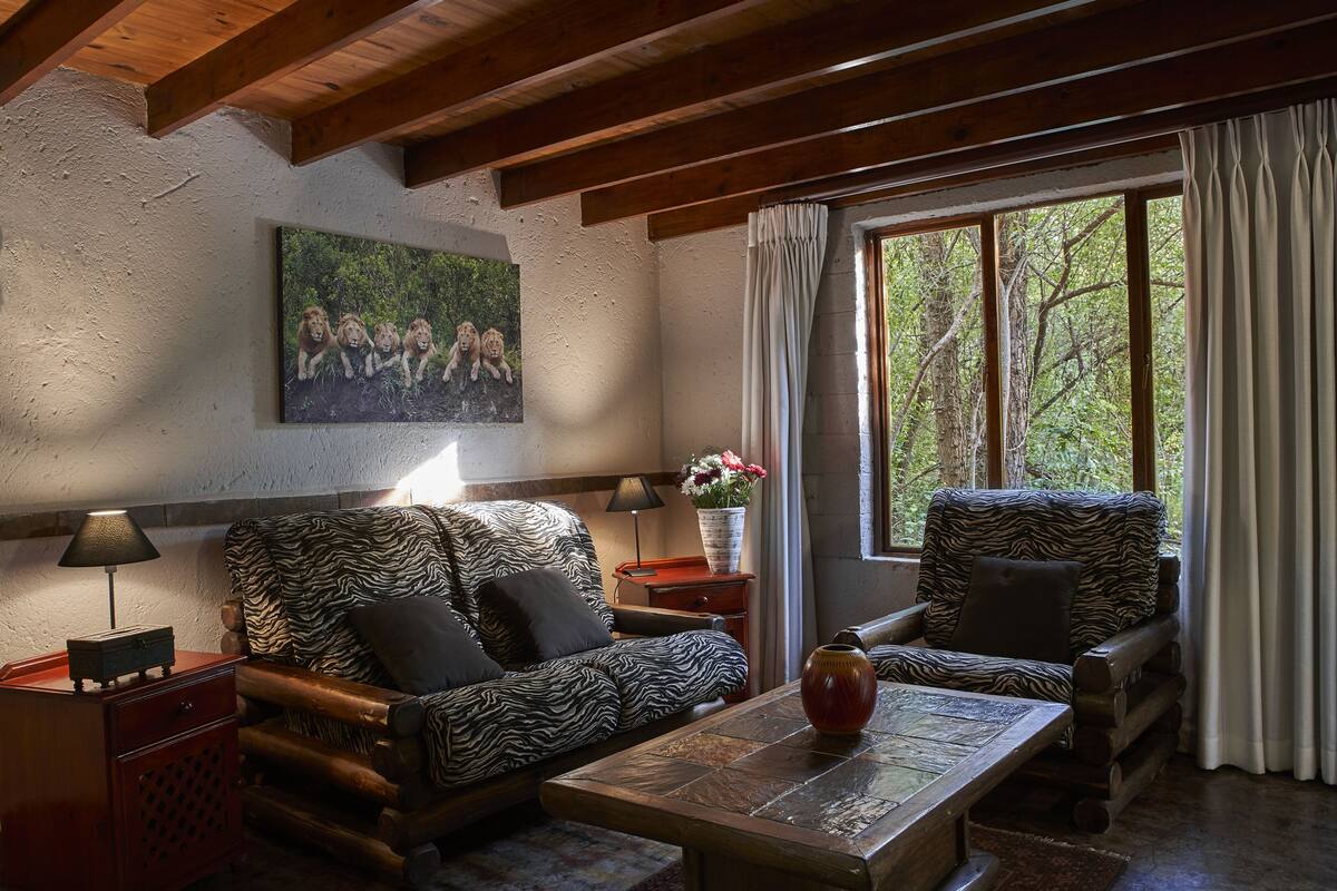 Ein gemütliches Wohnzimmer mit einem zebramusterten Sofa, einem Holztisch und einem Löwenbild an der Wand.