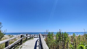 A wooden boardwalk leading to a beach with clear skies.