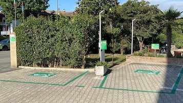 Un área de estacionamiento pavimentada con marcas en verde para ciclovía, un seto y una farola.