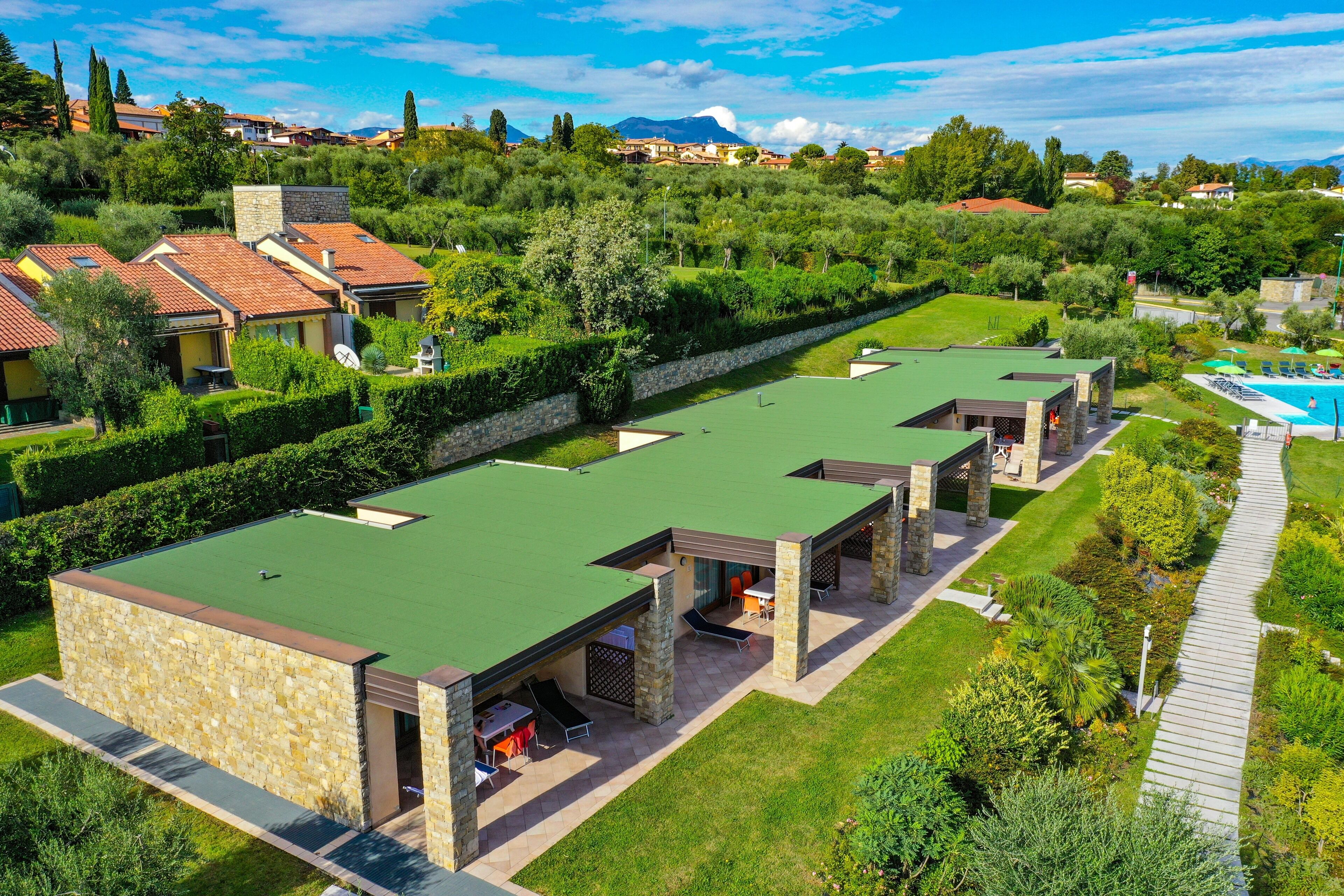 Uma vila moderna com telhado verde, paredes de pedra e área de piscina.