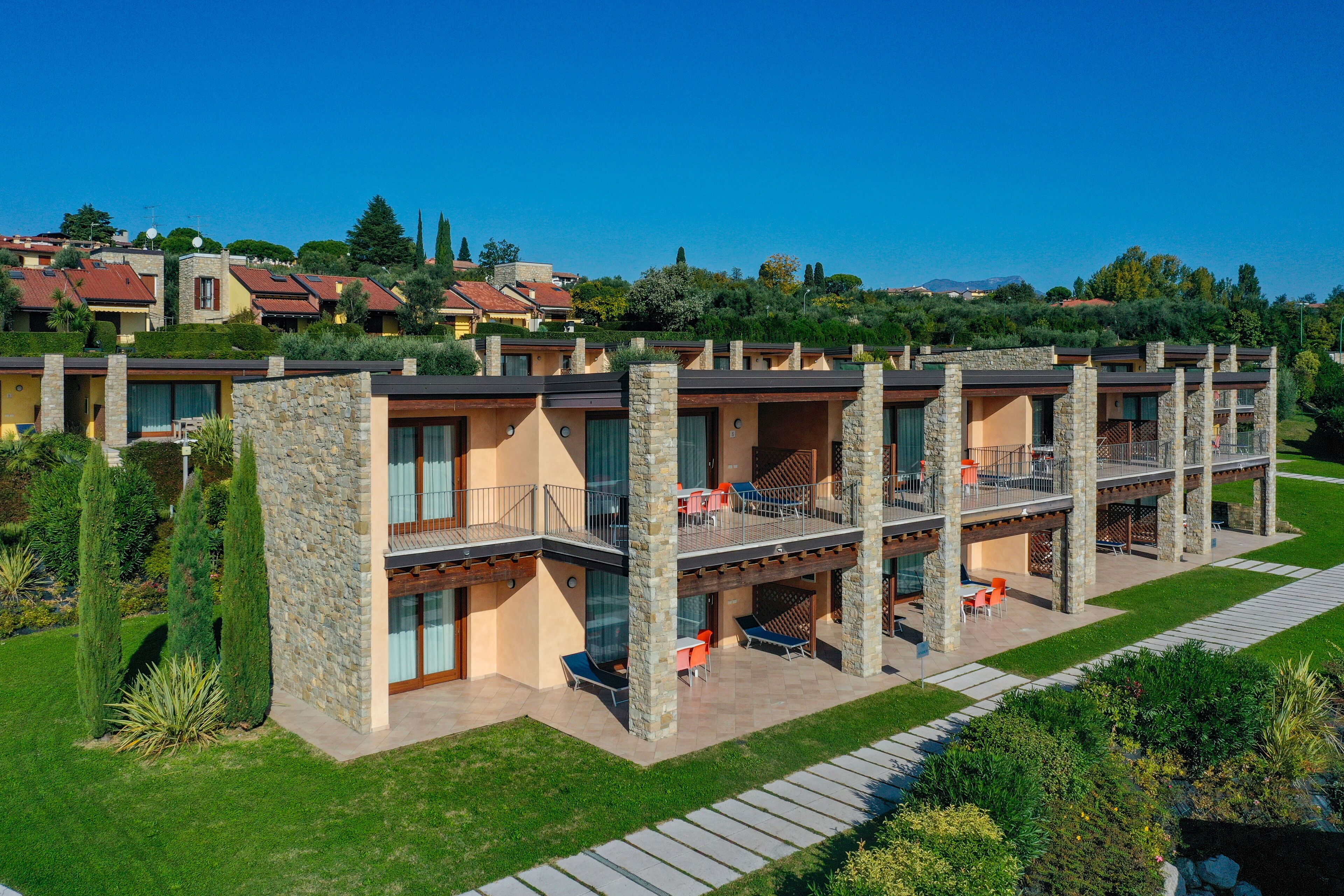 A multi-story hotel with balconies, outdoor seating, and a landscaped garden.