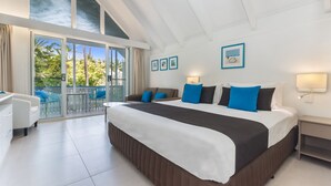 A spacious bedroom with a large bed, a balcony with chairs, and a ceiling fan. - By The Sea Port Douglas (Port Douglas)