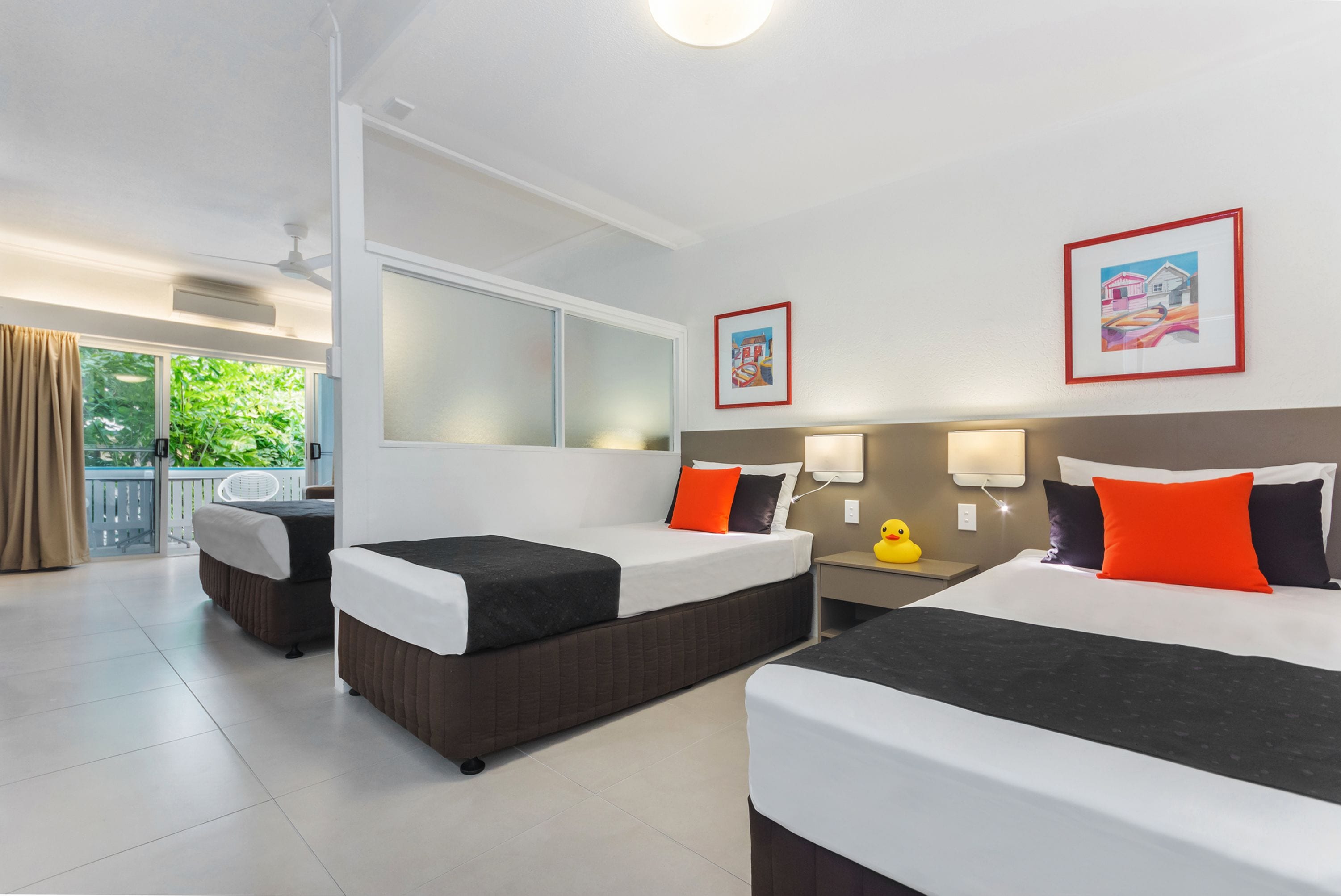 A hotel room with two beds, a balcony, and a large window.