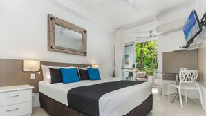 A modern bedroom with a large bed, a desk, and a chair. - By The Sea Port Douglas (Port Douglas)