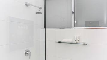 Une salle de bain moderne avec une douche à parois de verre, un porte-rouleau de papier toilette et un porte-serviettes.