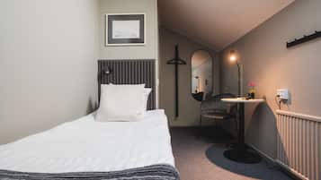 Een hotelkamer met een bed, een bureau, een stoel, een spiegel en een radiator.