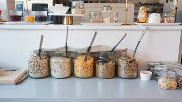 Una encimera de cocina con frascos de cereales y especias, una máquina de café y un dispensador de miel.