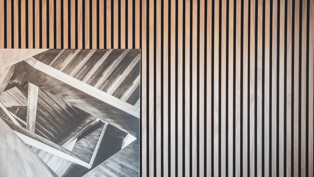 A modern interior with a slatted wall, a sofa, a chair, and a table. - VICI Hotels Linköping (Linkoping)