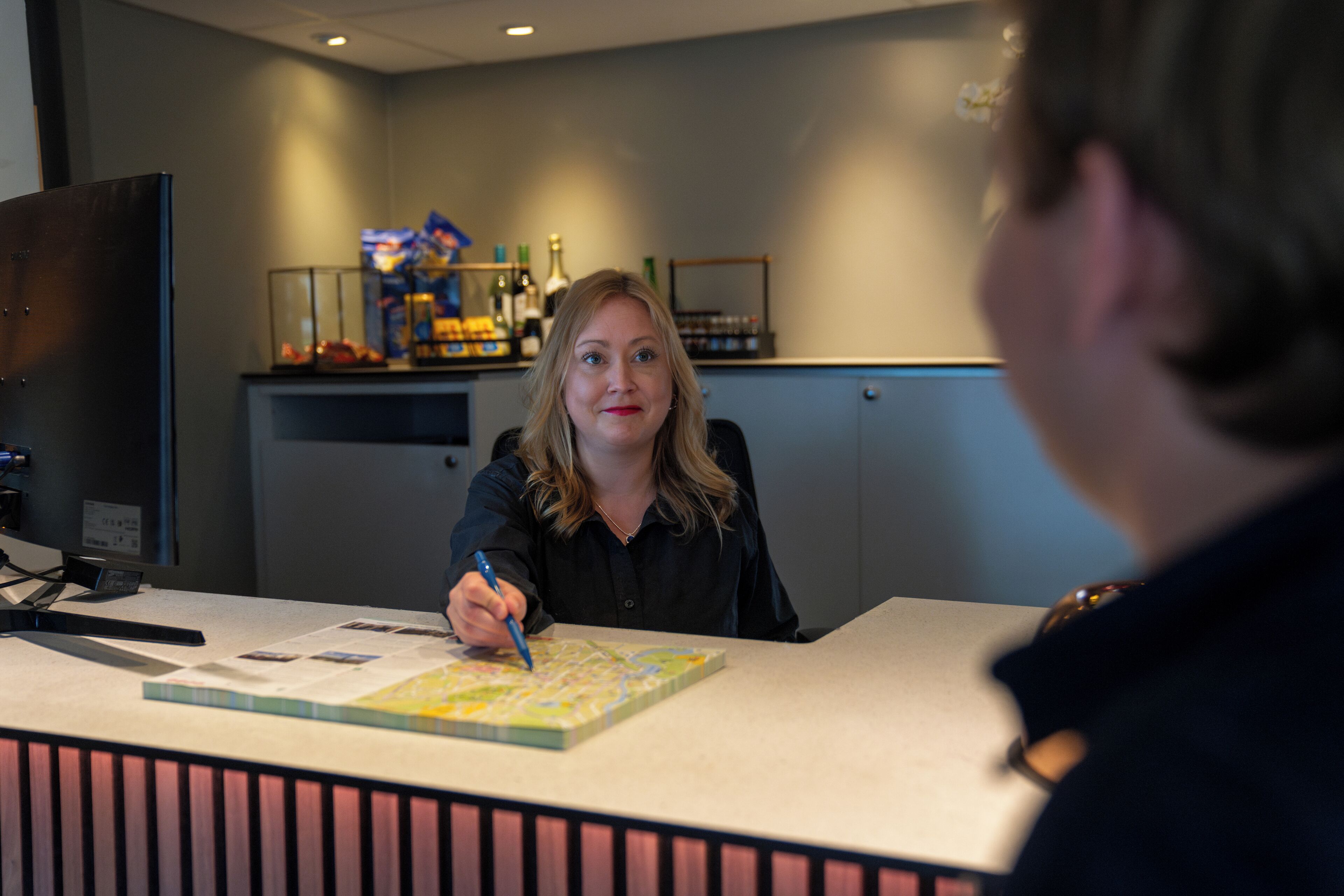 A reception desk with a map and a pen, a counter with various items, and a bar area in the background.