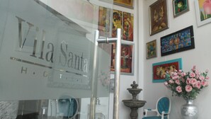 Interior de un hotel con una pared de vidrio que muestra el nombre 'Vila Santa'.