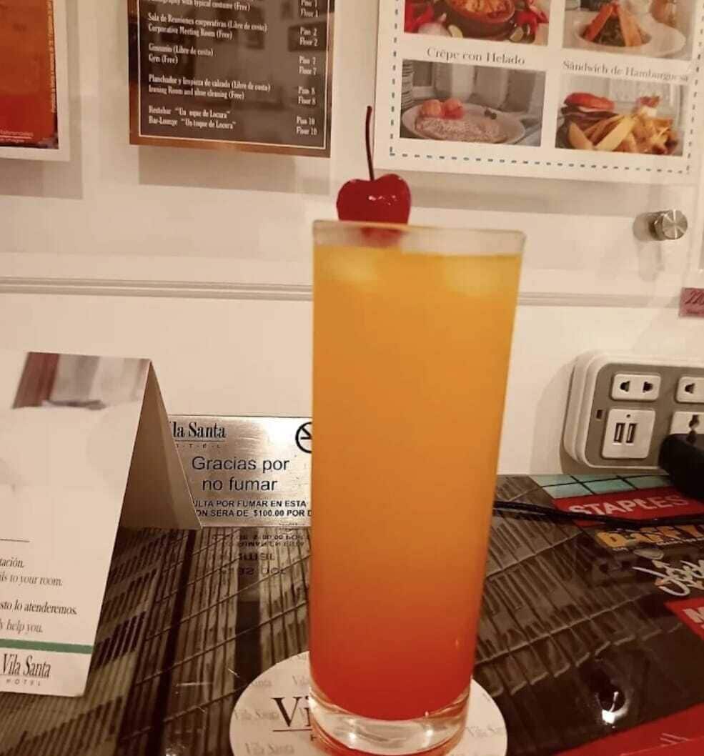 A tall glass with a gradient drink, a menu board, and a hotel sign.