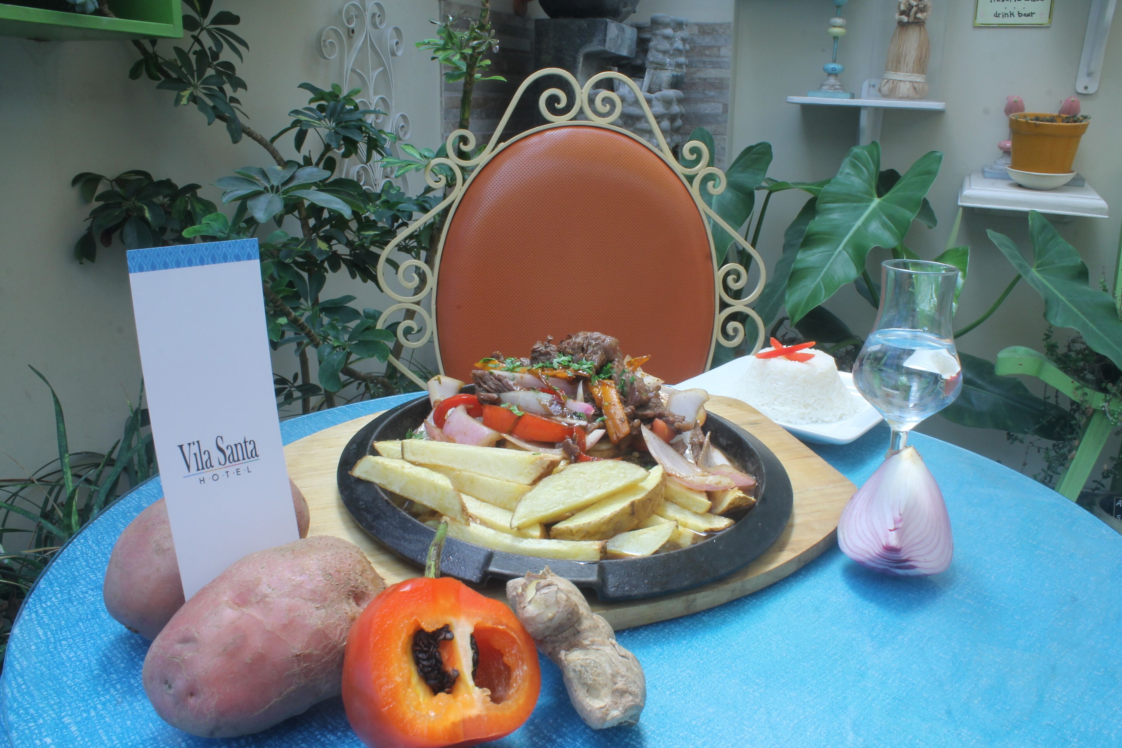 A table with a plate of food, a bottle of water, and a sign for Vila Santa Hotel.