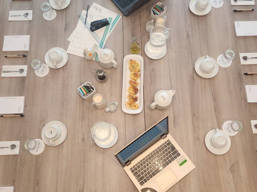 Une table en bois sur laquelle se trouvent un ordinateur portable, des théières, des tasses et un plateau de nourriture.