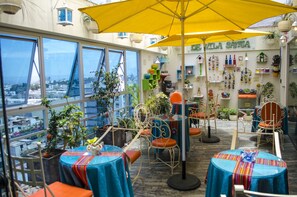 A rooftop terrace with tables and chairs, potted plants, and a view of the city. - Hotel Vila Santa (Lima)