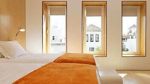 A room with a bed, a bench, and three windows. - Hotel Holos (Seville)
