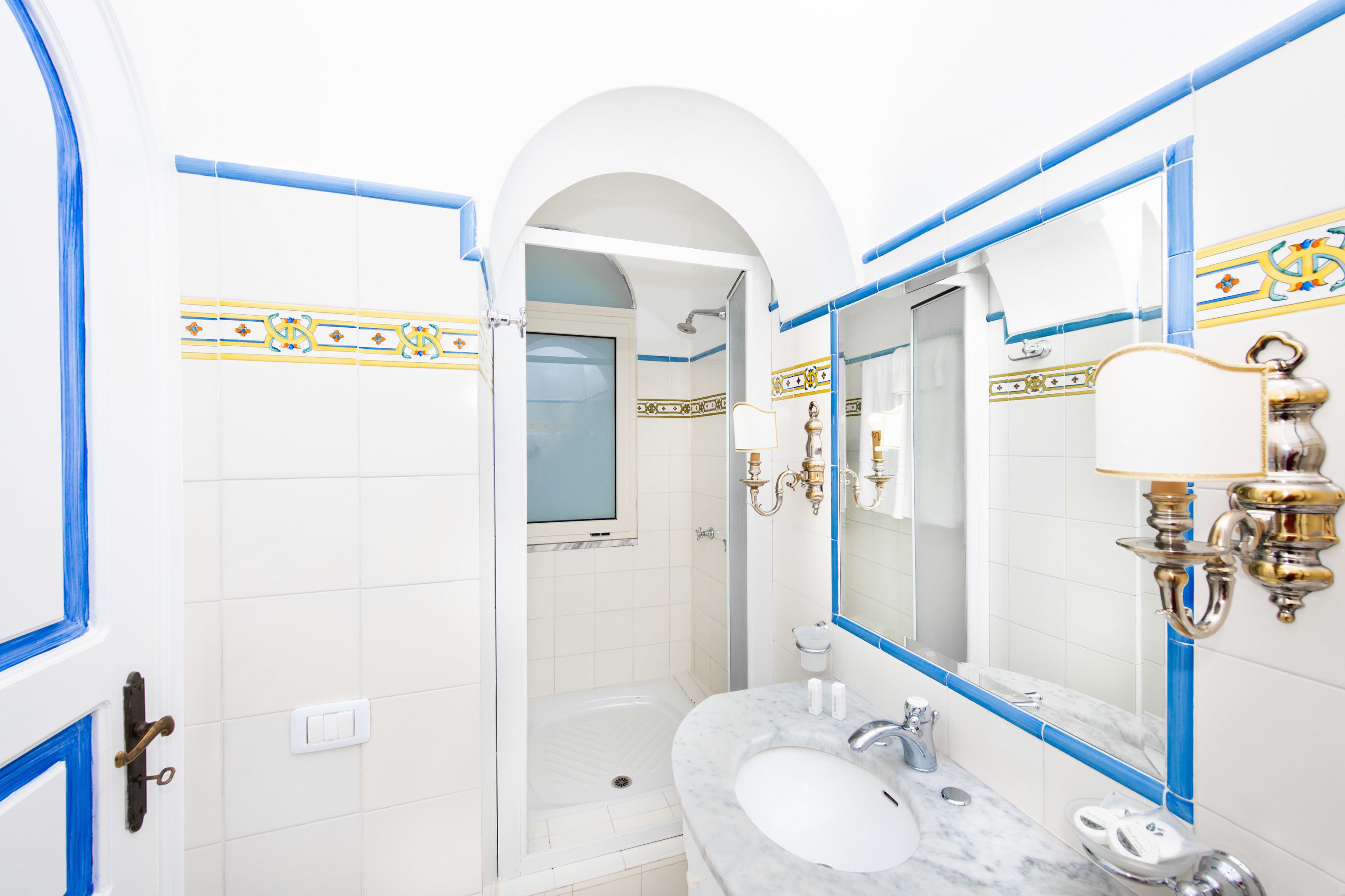 Een badkamer met een witte wastafel, een spiegel en blauwe betegelde wanden.