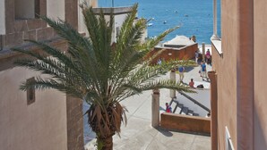 A courtyard with a palm tree, a building with a bell tower, and a view of the sea. - Villa Flavio Gioia (Positano)