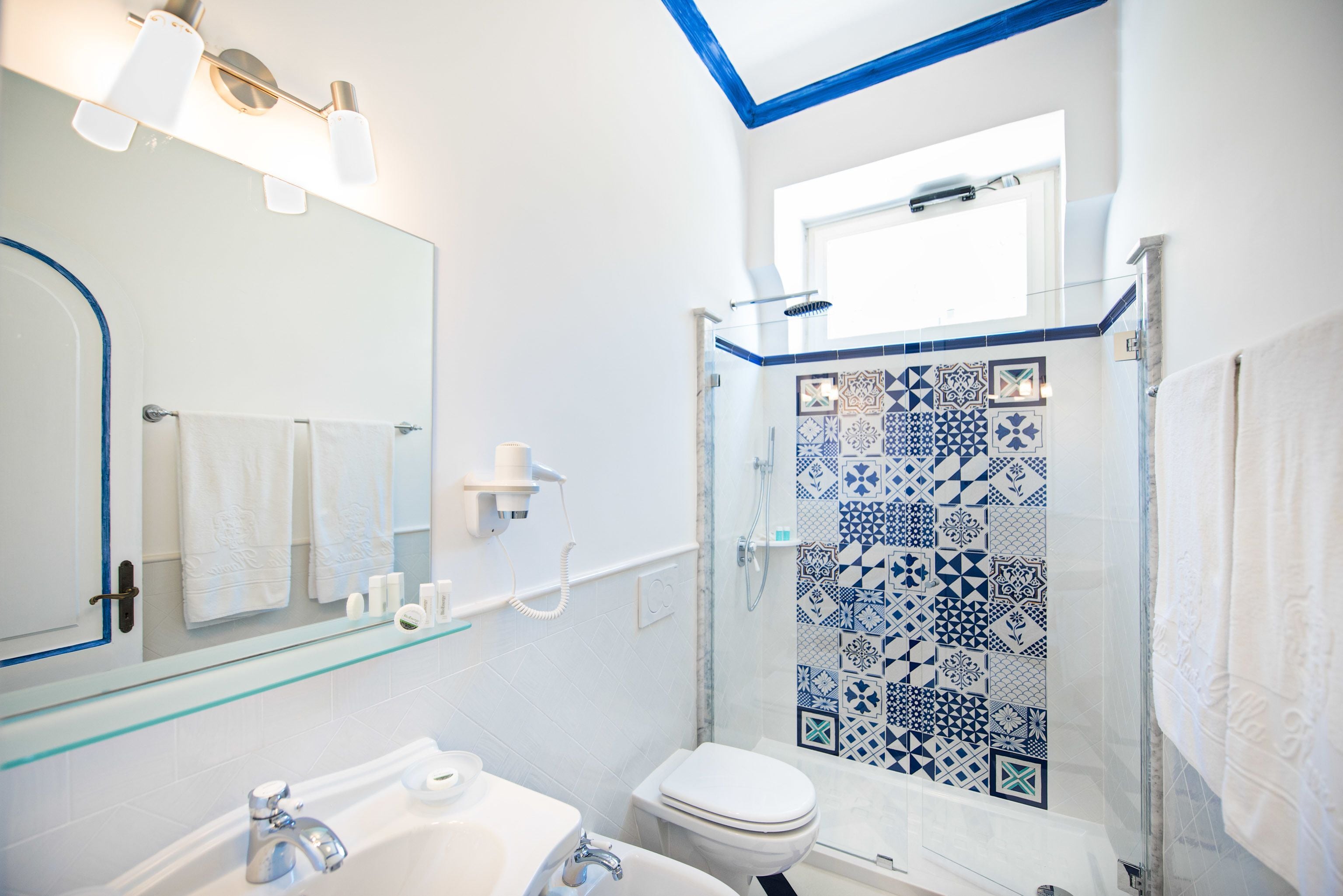 Un bagno con cabina doccia in vetro, un lavandino bianco e un water.