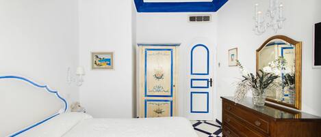 Un dormitorio con cama, cómoda y puerta decorada con motivos florales.