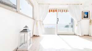 A bright room with a large window, white curtains, a white lantern, and a view of the sea. - Villa Flavio Gioia (Positano)