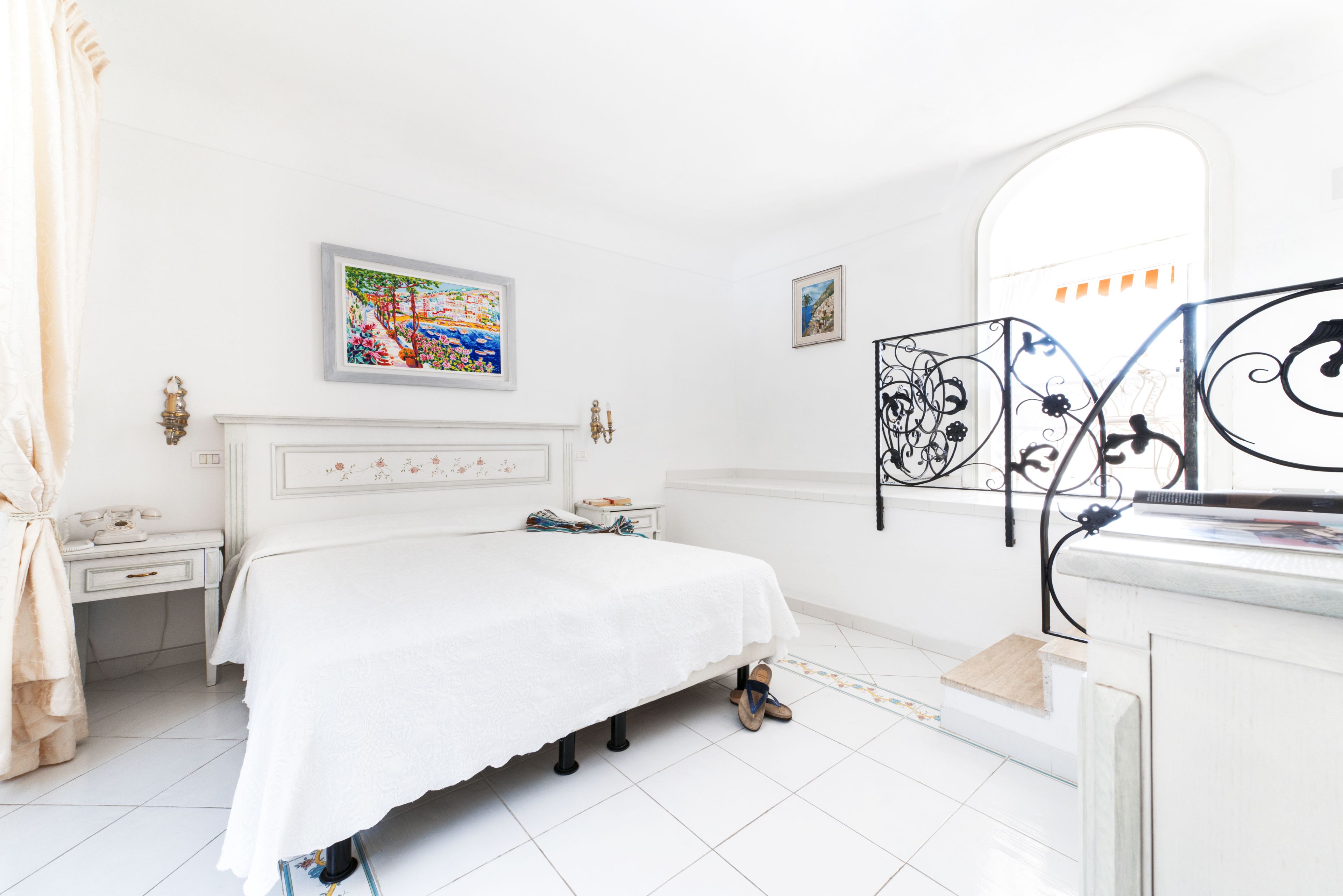 A white bedroom with a bed, a nightstand, a dresser, and a mirror.