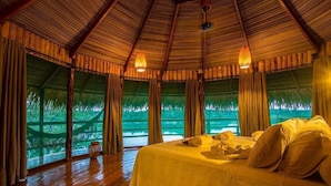 A room with a bed, wooden floors, and a thatched roof. - Juma Amazon Lodge (Autazes)