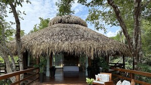 A wooden deck leading to a thatched-roof structure with a bed and seating area. - Juma Amazon Lodge (Autazes)