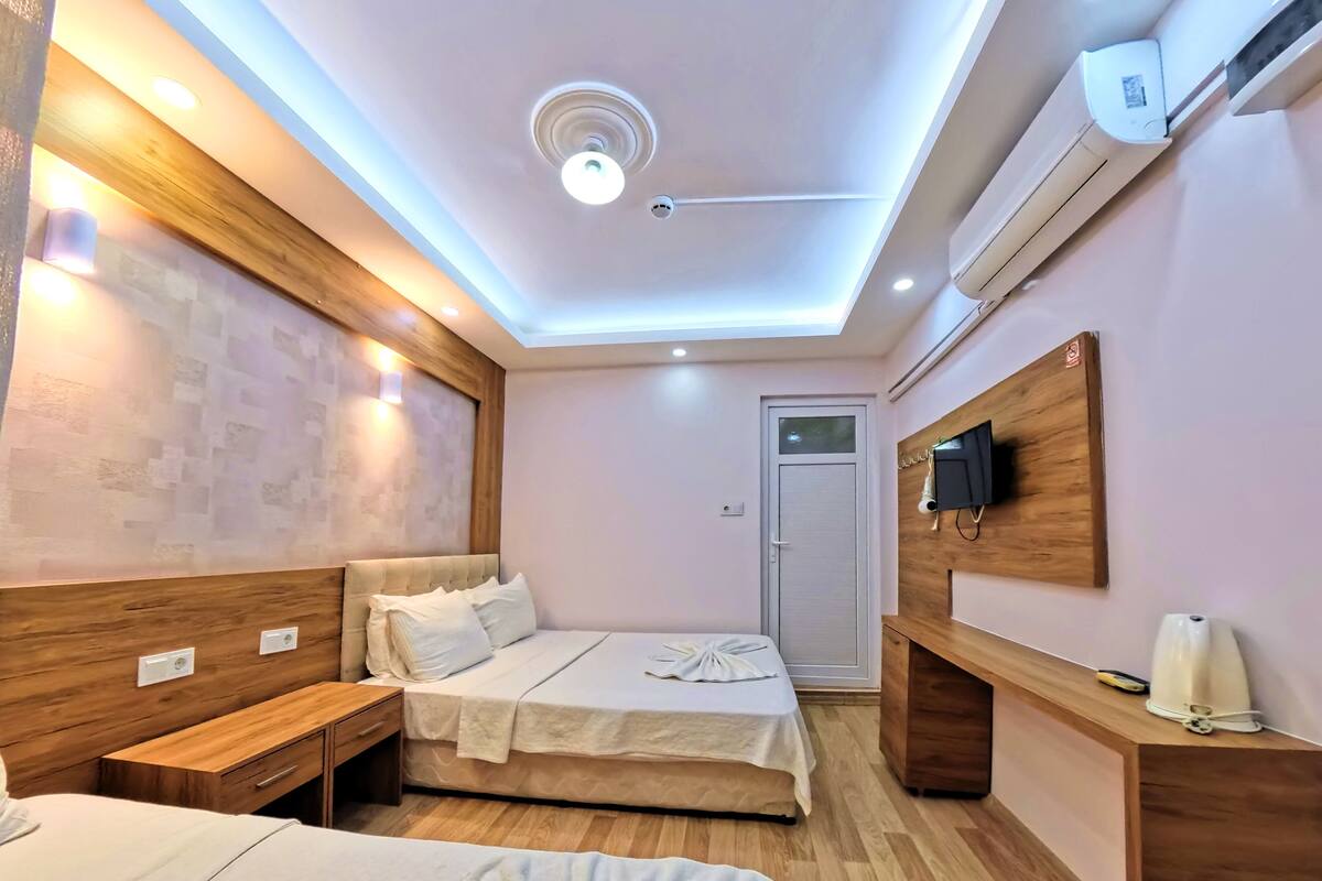 A hotel room with a bed, bedside table, and a desk with a chair.