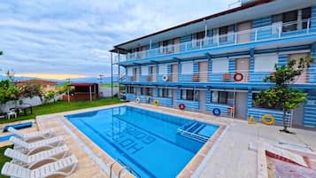 Un hotel con piscina, varios balcones y vistas a la montaña.