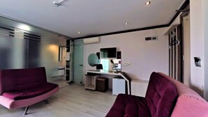 A modern living room with a sofa, a small desk, and a television. - Goreme Sakura  (Denizli)
