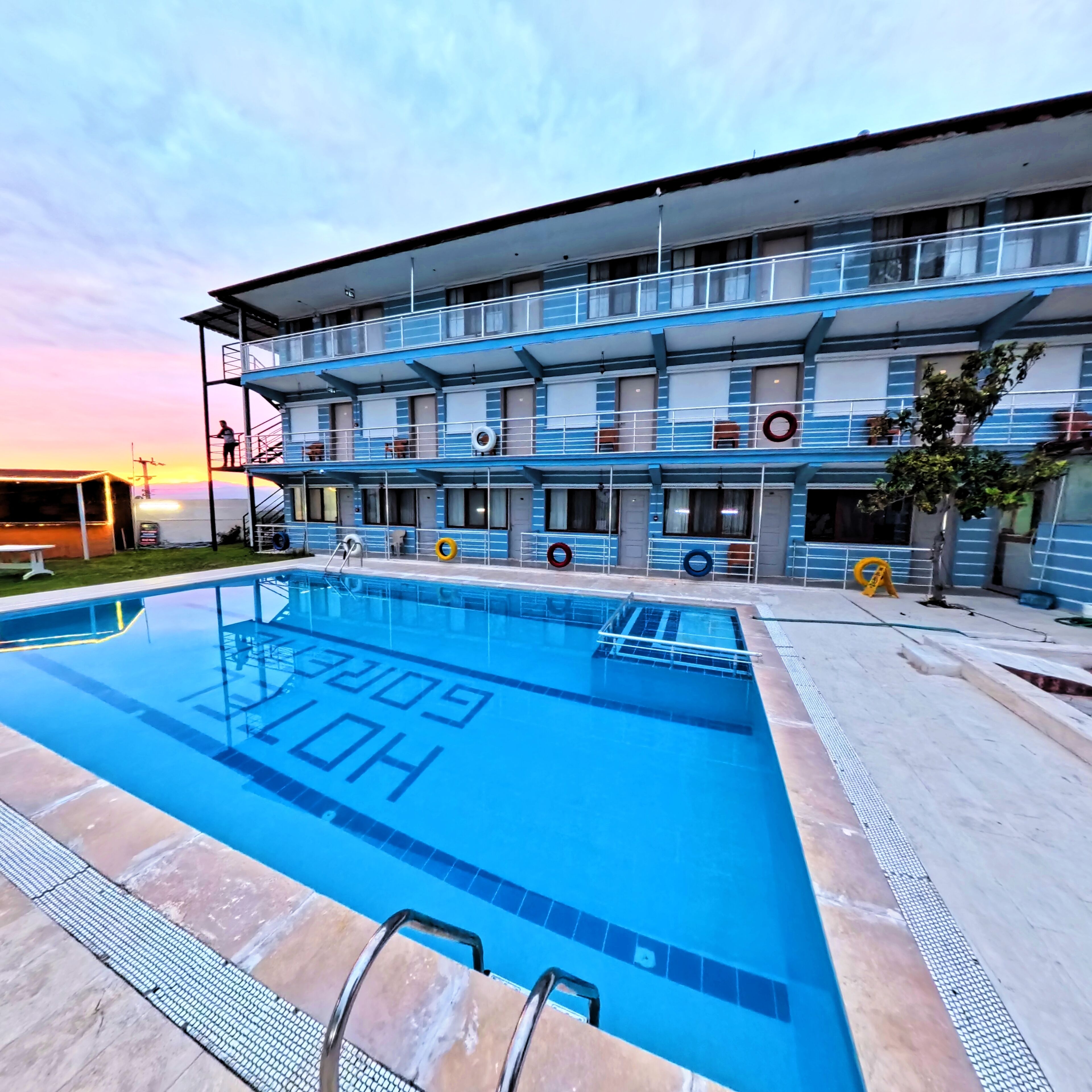 Un hôtel doté d’une piscine, de plusieurs balcons et offrant une vue sur le coucher de soleil.