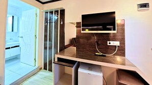 A modern room with a built-in TV, a small fridge, a coat rack, and a door leading to a bathroom. - Goreme Sakura  (Denizli)