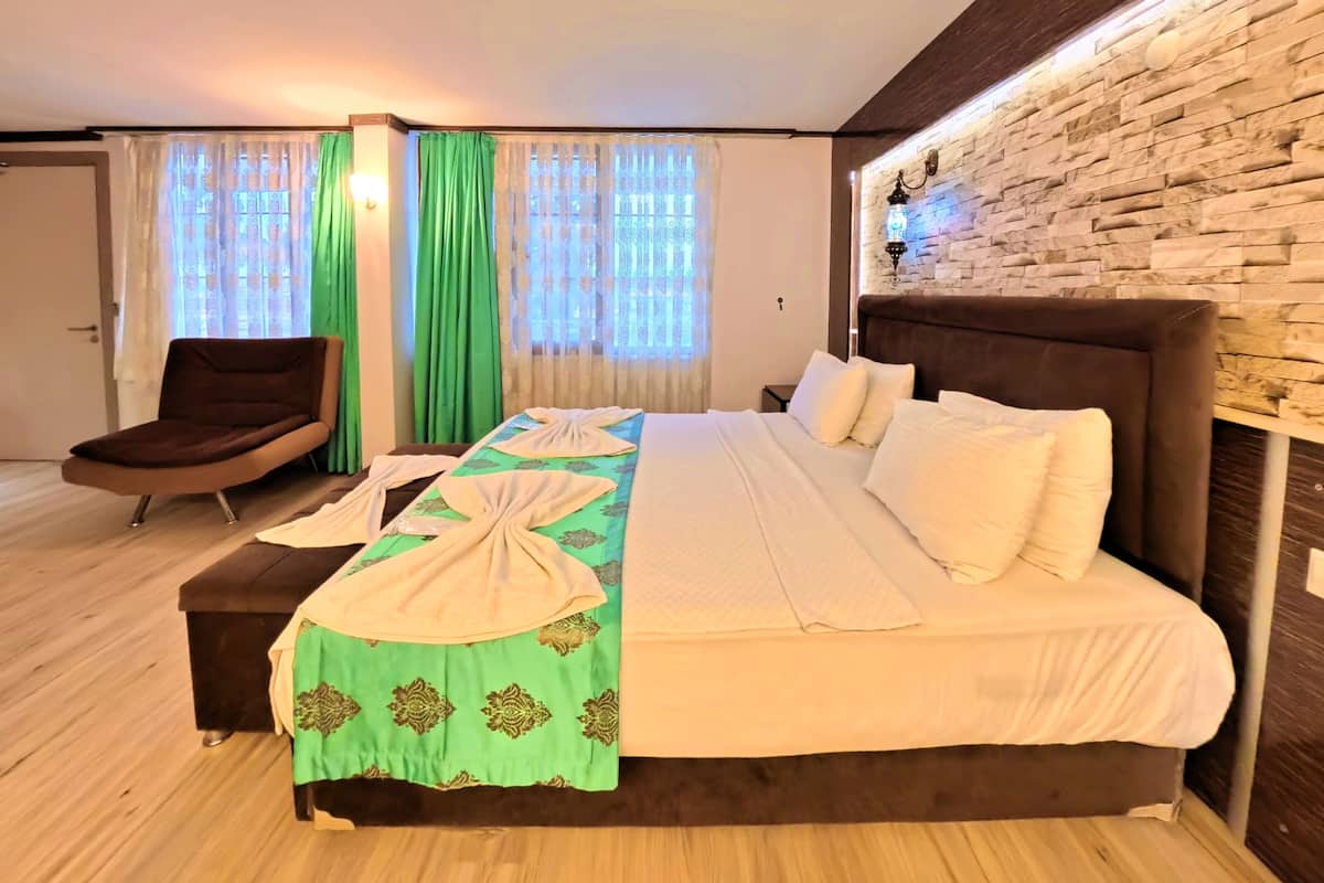 A neatly arranged bedroom with a large bed, a chair, and a wall-mounted lamp.