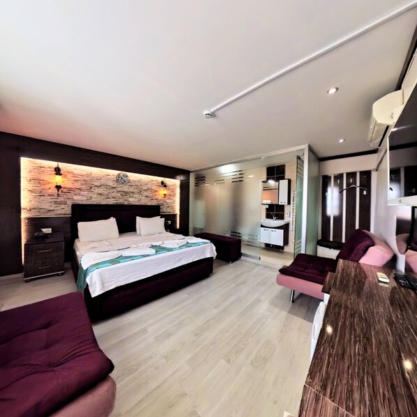 Un dormitorio moderno con cama, mesitas de noche, tocador y zona de estar.