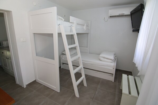 Habitación con literas, una escalera, un televisor y una mesita pequeña.