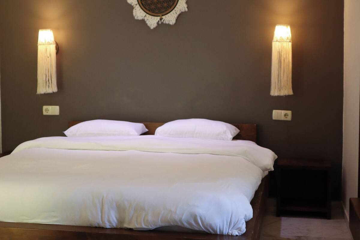 Une chambre à coucher avec un lit en bois, deux lampes fixées au mur et un élément décoratif mural.