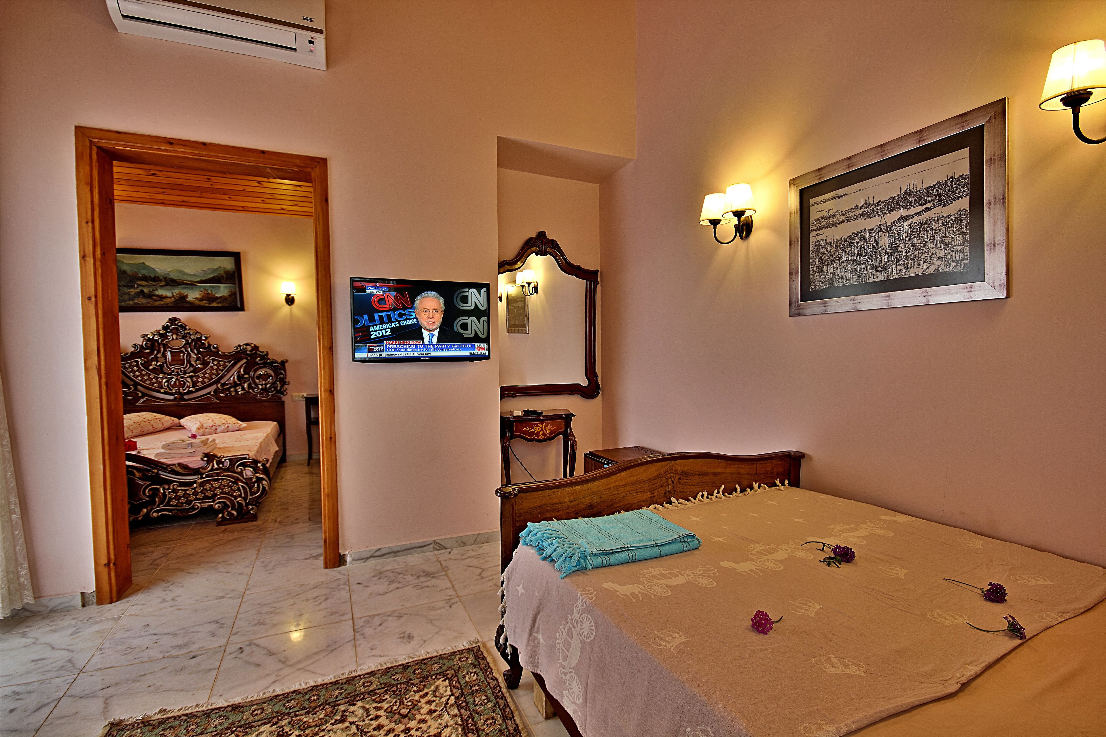 A bedroom with a bed, a television, a painting, and a lamp.