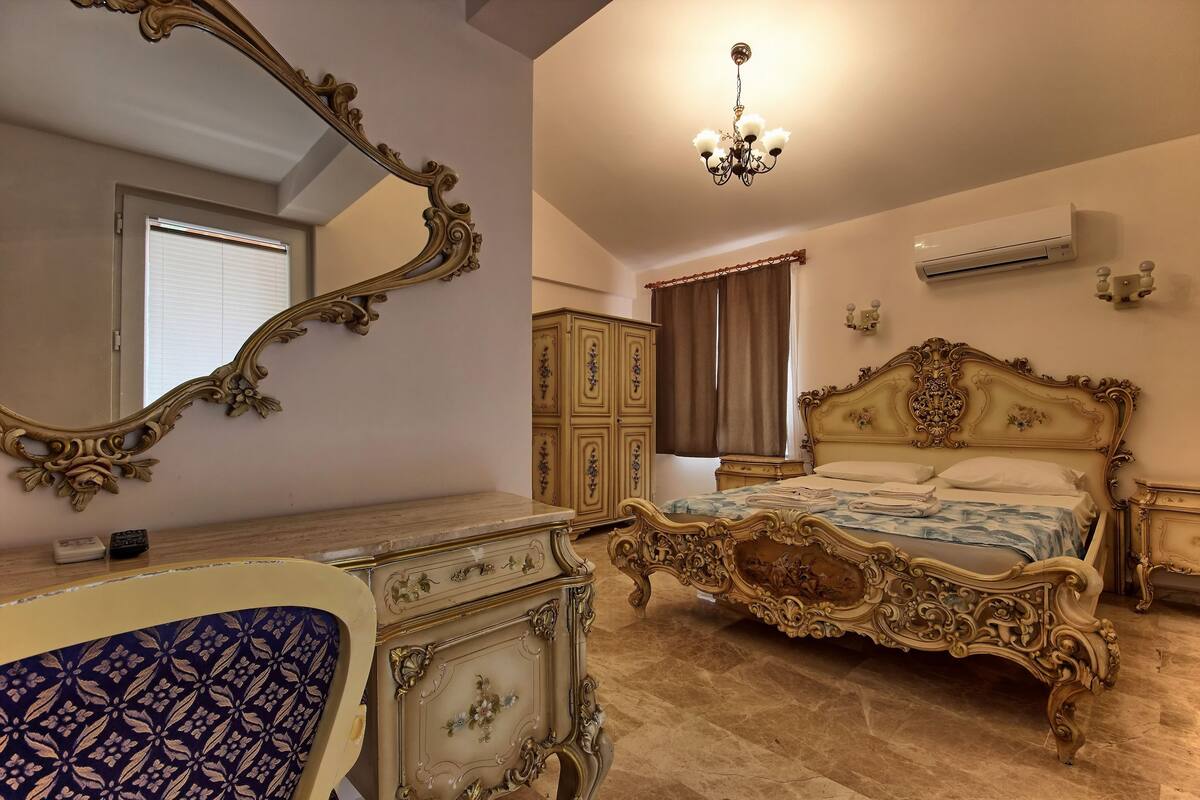 Une chambre à coucher avec un grand lit à baldaquin décoré, une commode assortie et un miroir.