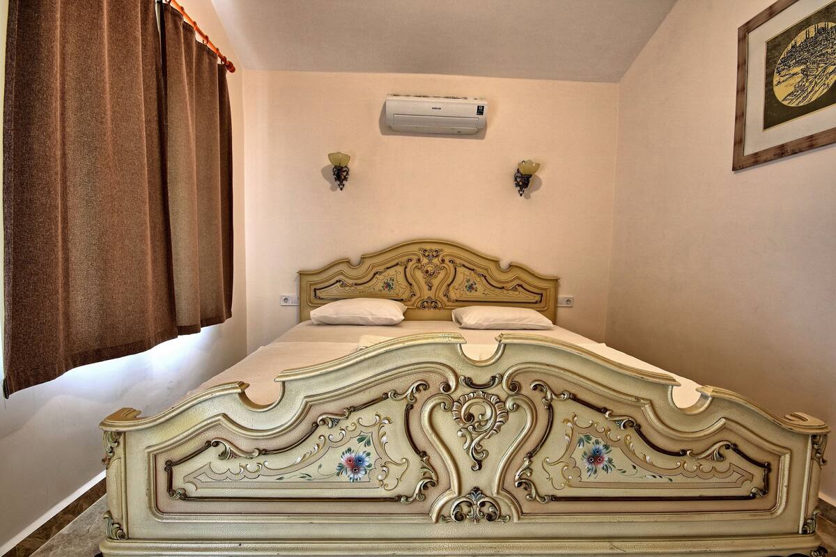 Une chambre dotée d’un grand lit, d’un climatiseur et de deux lampes fixées au mur.
