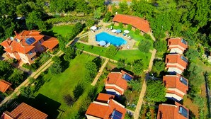 Vista aérea de un área residencial con varias casas, una piscina y un césped bien cuidado.