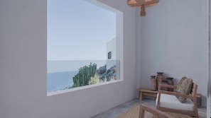 A modern room with a large window overlooking a rocky coastline.